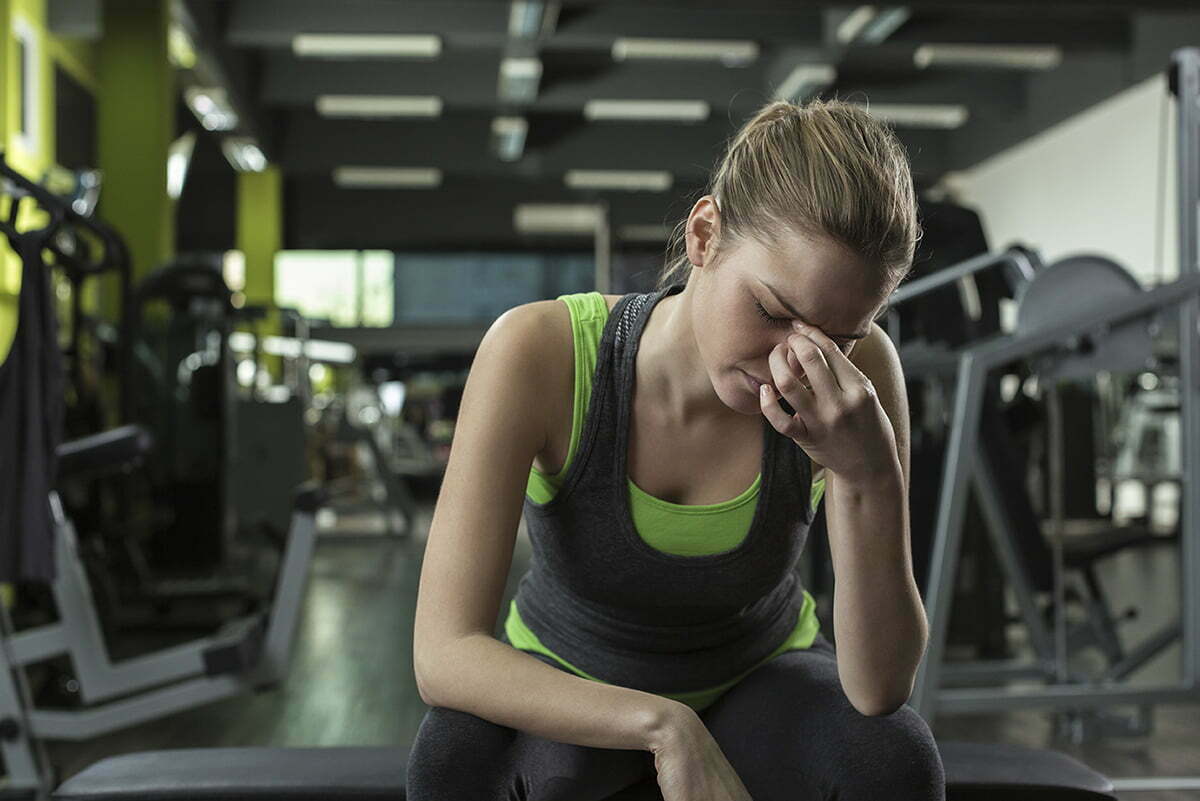 Woman with a headache sitting at the gym